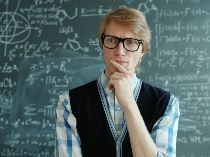 homem a pensar e quadro com fórmulas cientificas atrás